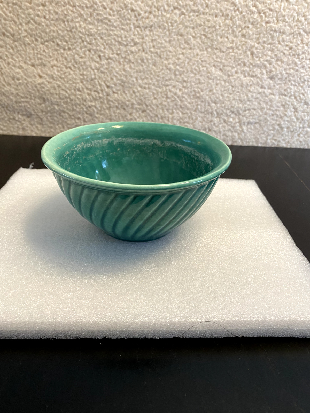A vintage Chinese green porcelain bowl with waves around the side