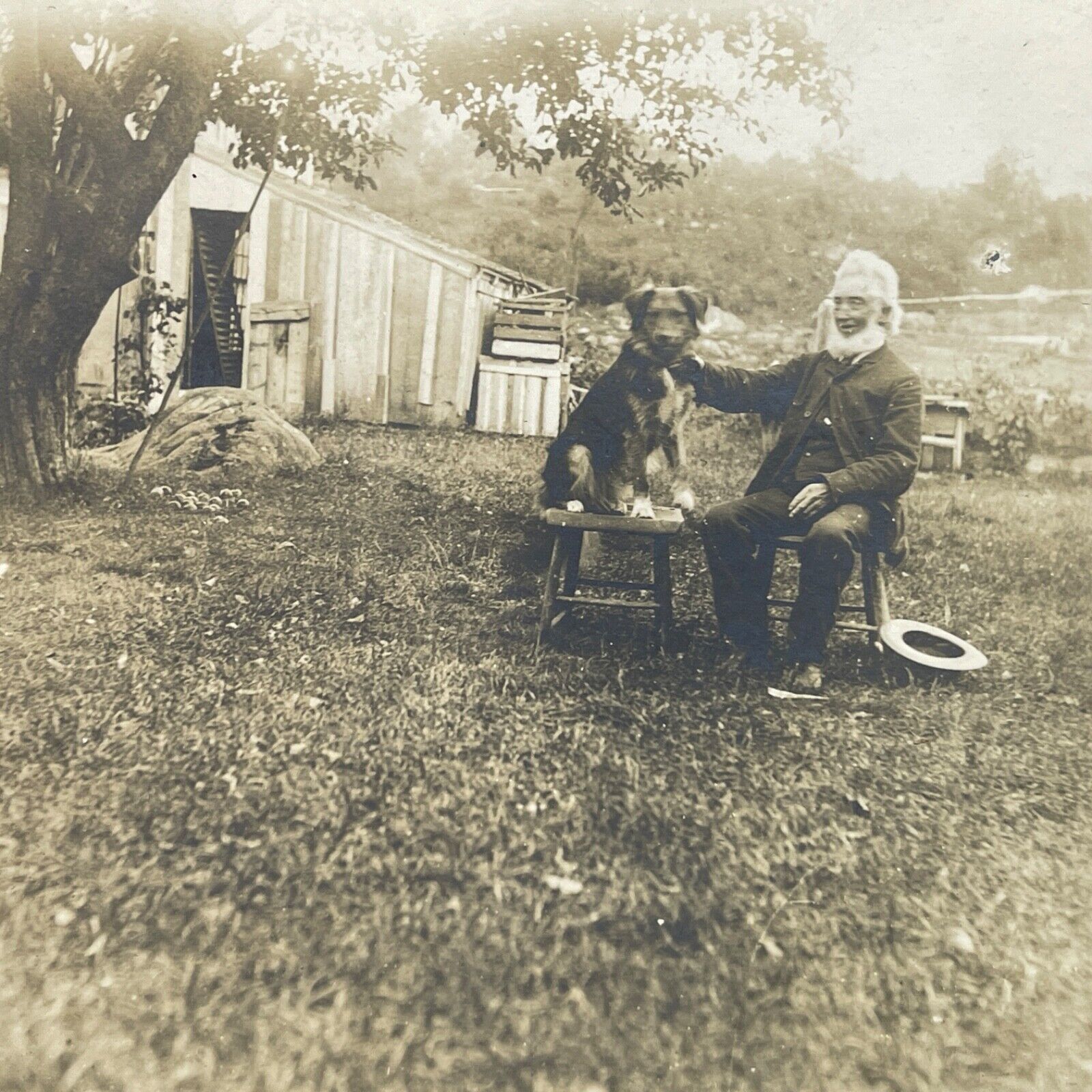 Antique Photo Board Mounted Older Man with Dog Sitting on Stools Outside Shed