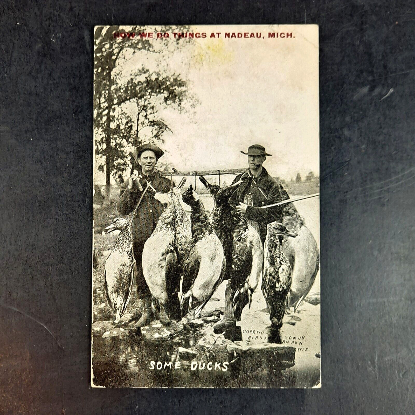 ANTIQUE 1912 EXAGGERATION POST CARD SOME DUCKS DUCK HUNTERS NADEAU, MI POSTCARD