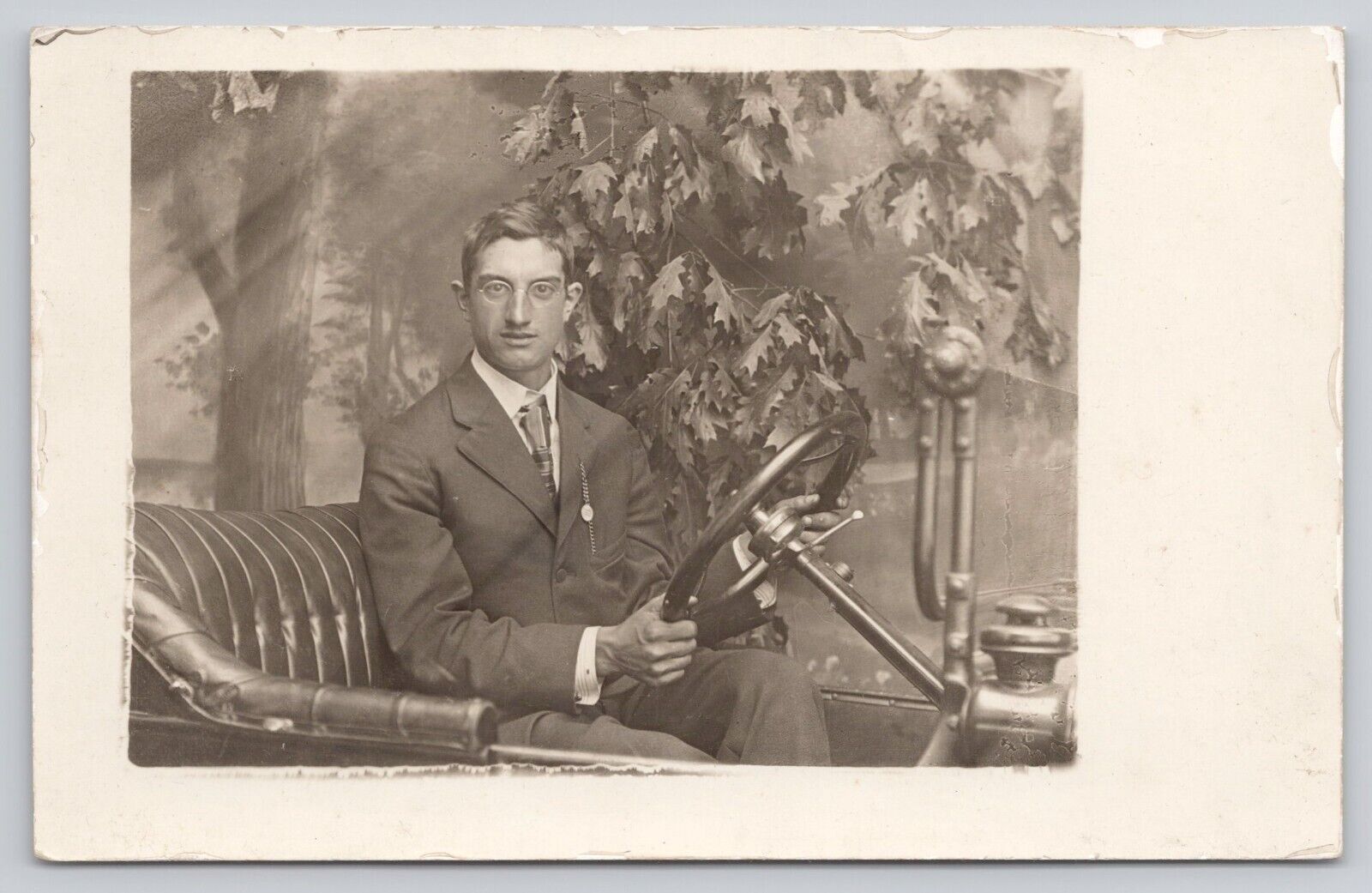 Man in Suit Glasses Sitting in a Prop Antique Car PMO c1907-1915 RPPC Postcard
