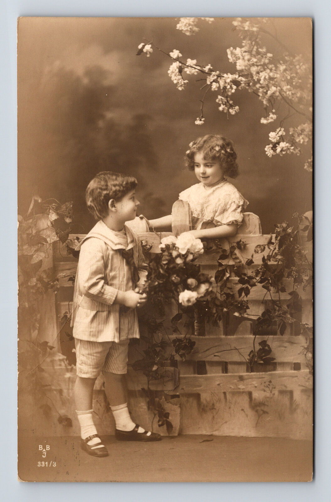 c1913 RPPC Studio Portrait of Boy Giving Girl Flowers Postcard