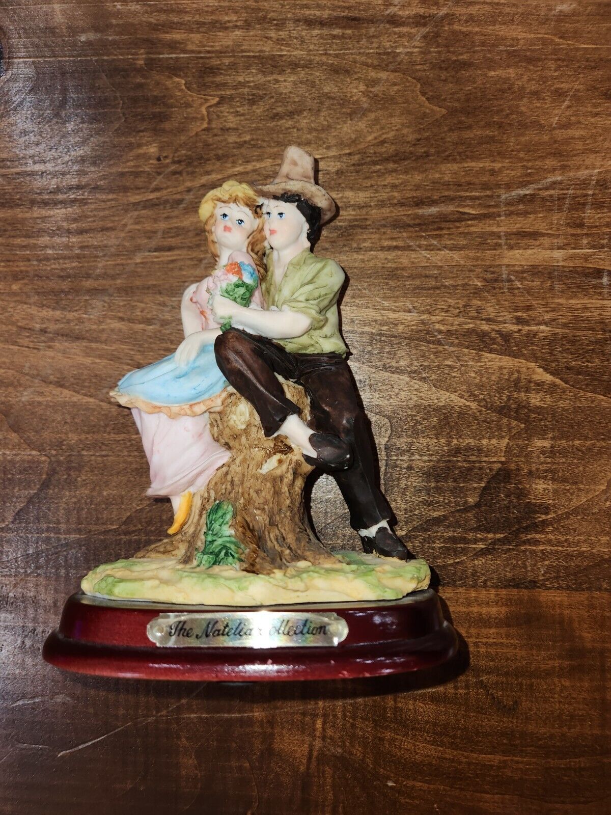 The Natelia Collection Figurine of man and woman sitting on stump on wooden base