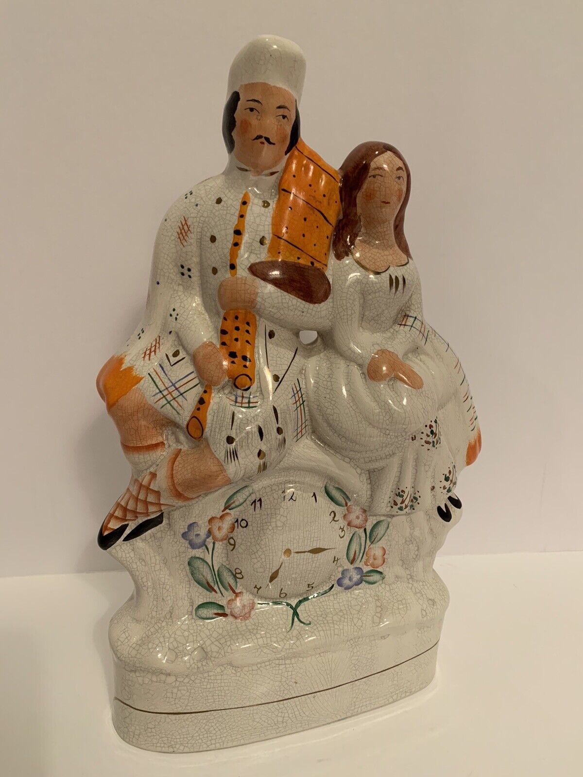 *Reproduction* Staffordshire figurine of man & woman sitting on a clock