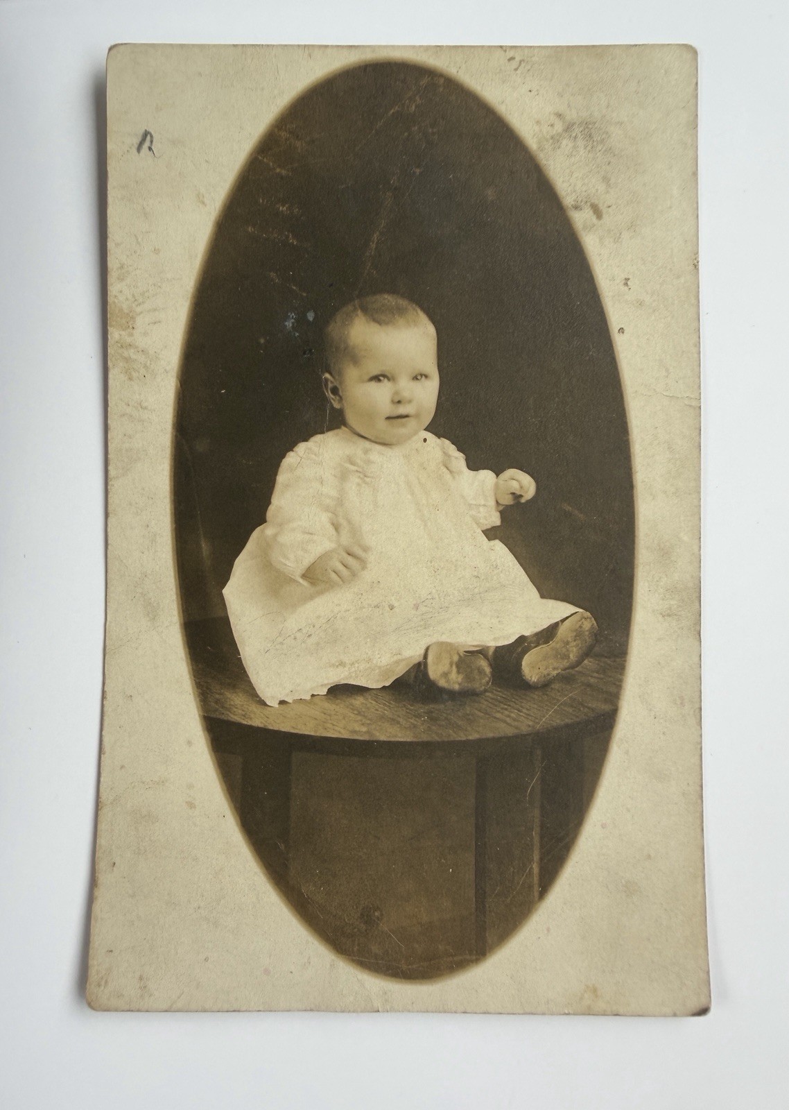 RPPC 1900-1910 - Baby In White Dress Sitting On Wood Table - Photo Postcard