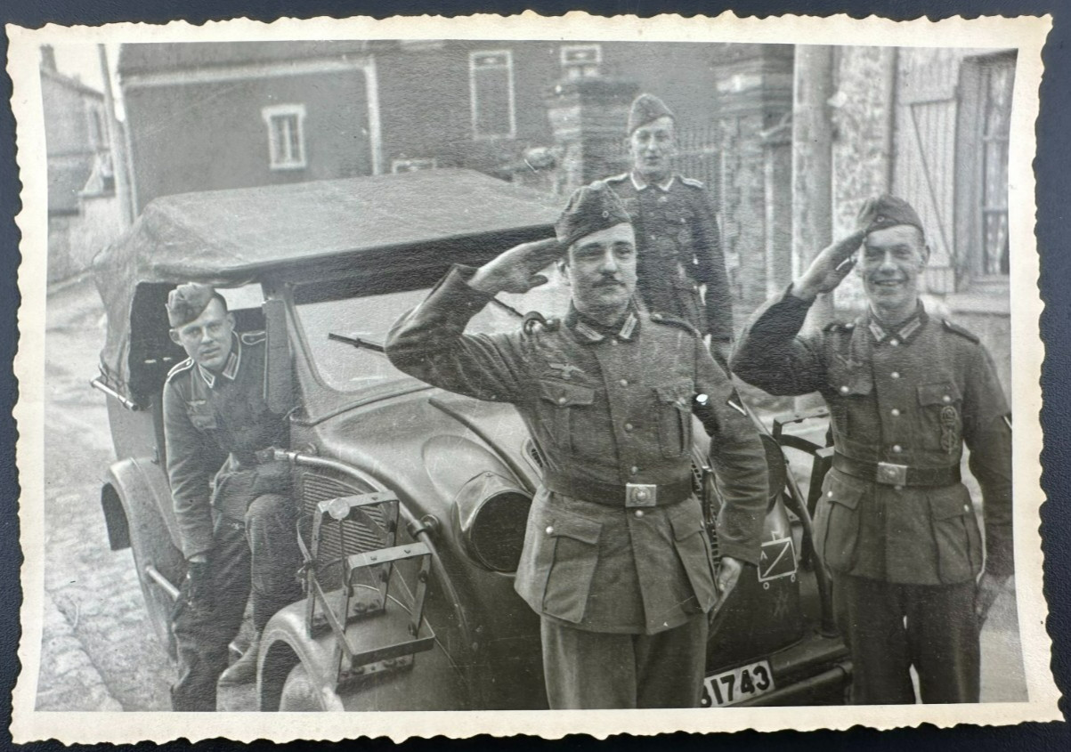 1943\'s WWII SS Wehrmacht soldiers standing next to a Steyr 250 vehicle.