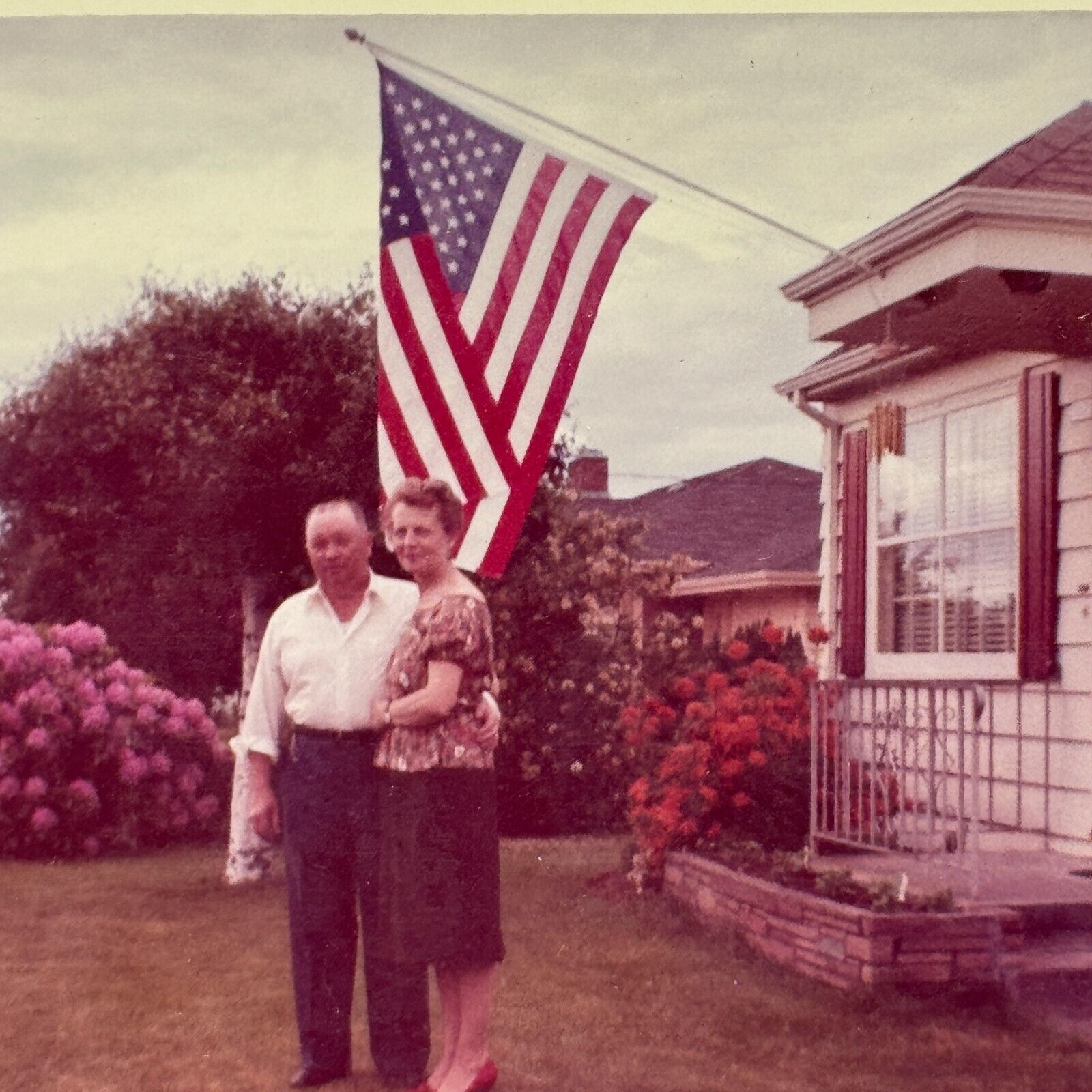 1T Photograph Cute Old Couple Posing Man Woman American Flag Grass Yard 1963