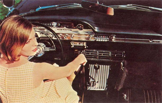 Young woman pictured from behind sits at the wheel of a car Old Photo