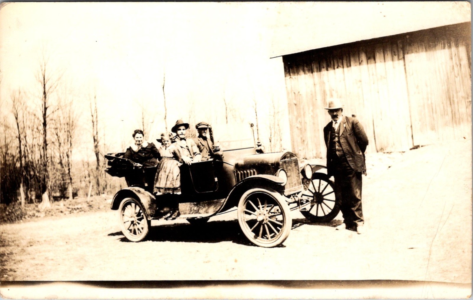 The postcard is an original real photo postcard of a vintage car and family .