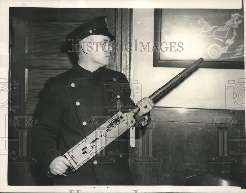 Press Photo Patrolman Gerald F. Bowen examining the machine gun found at school