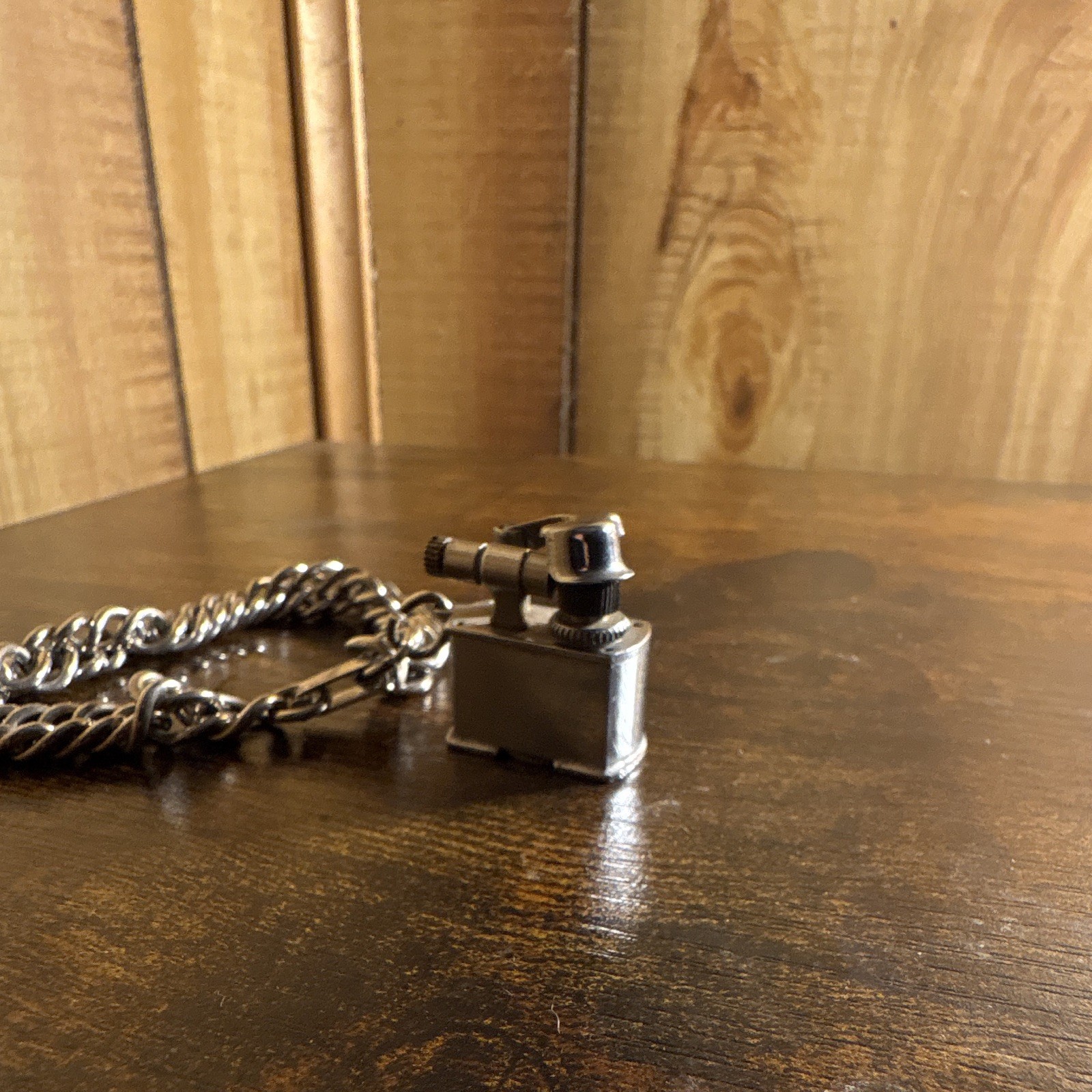 vintage miniature lift-arm cigarette lighter charm attached to a chain