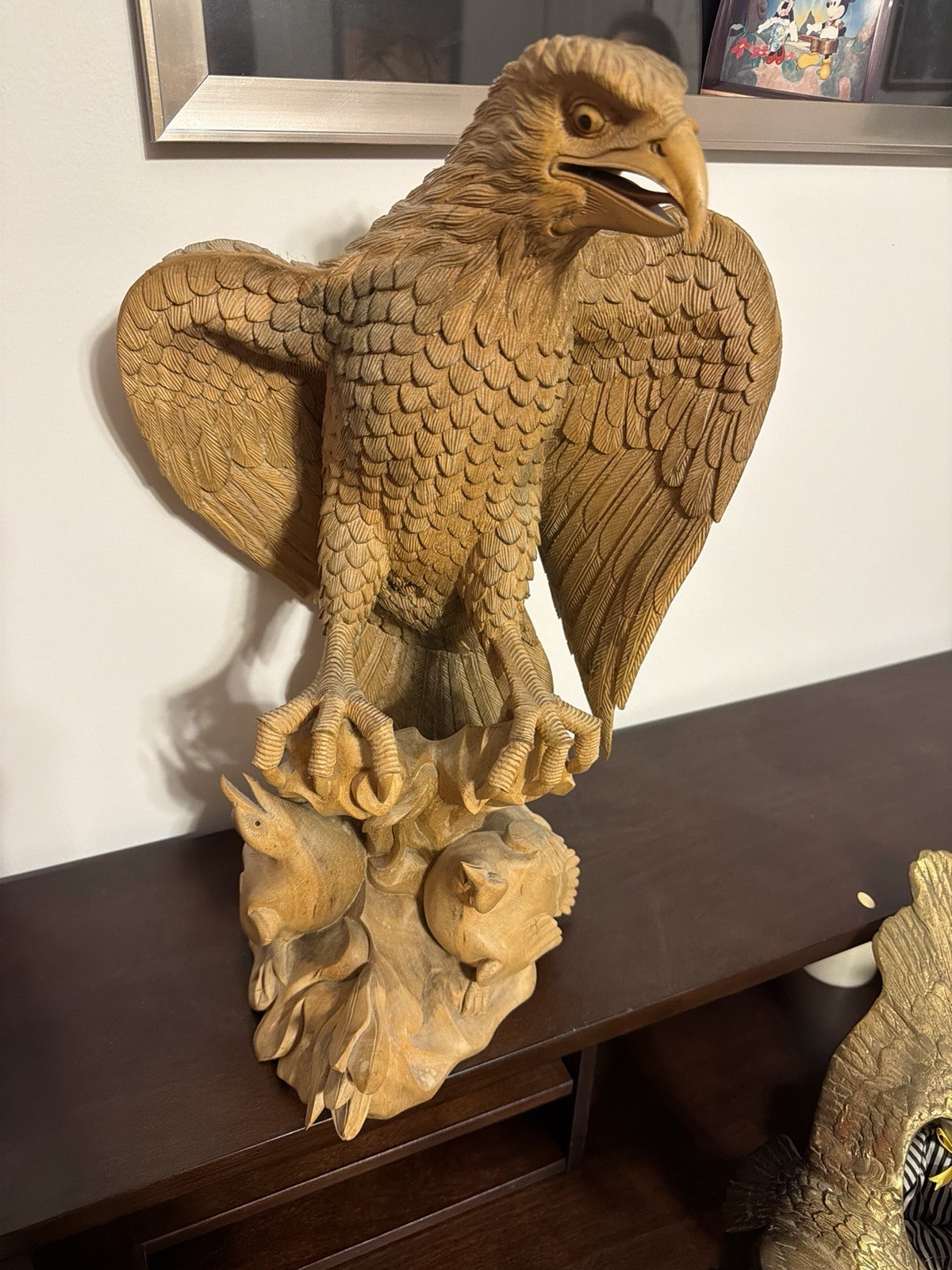 Handcrafted wooden sculpture of an eagle perched on a rocky base with fish/prey