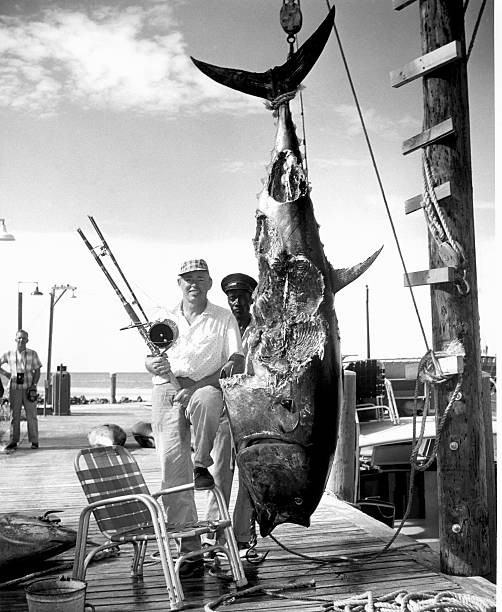 Two men stand a dock next a mutilated tuna caught near Cat Cay Bah- Old Photo