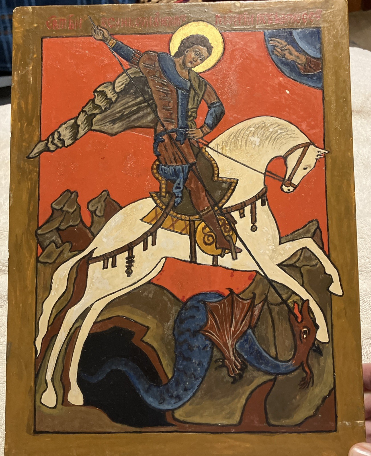 Saint George on a white horse piercing a coiled dark-blue dragon with a lance.