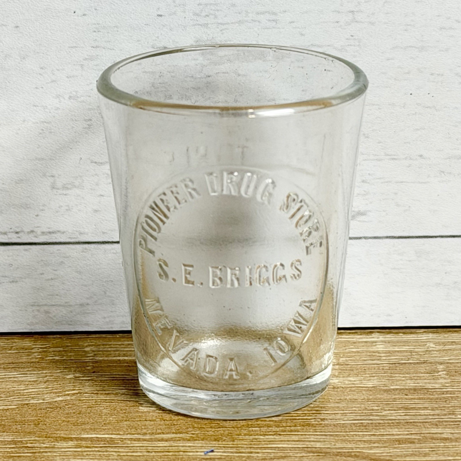ANTIQUE PIONEER DRUG STORE SHOT DOSE GLASS ADVERTISING NEVADA IOWA S E BRIGGS