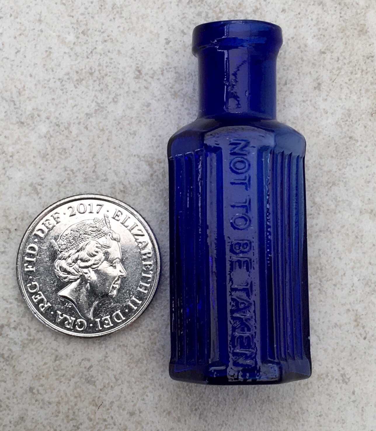 A MINIATURE ANTIQUE BLUE GLASS HEXAGONAL RIBBED POISON BOTTLE “NOT TO BE TAKEN”