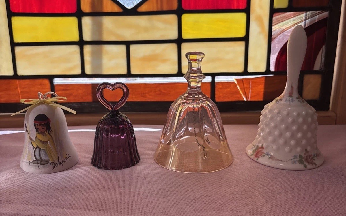 four decorative porcelain and glass bells or bell-shaped collectibles