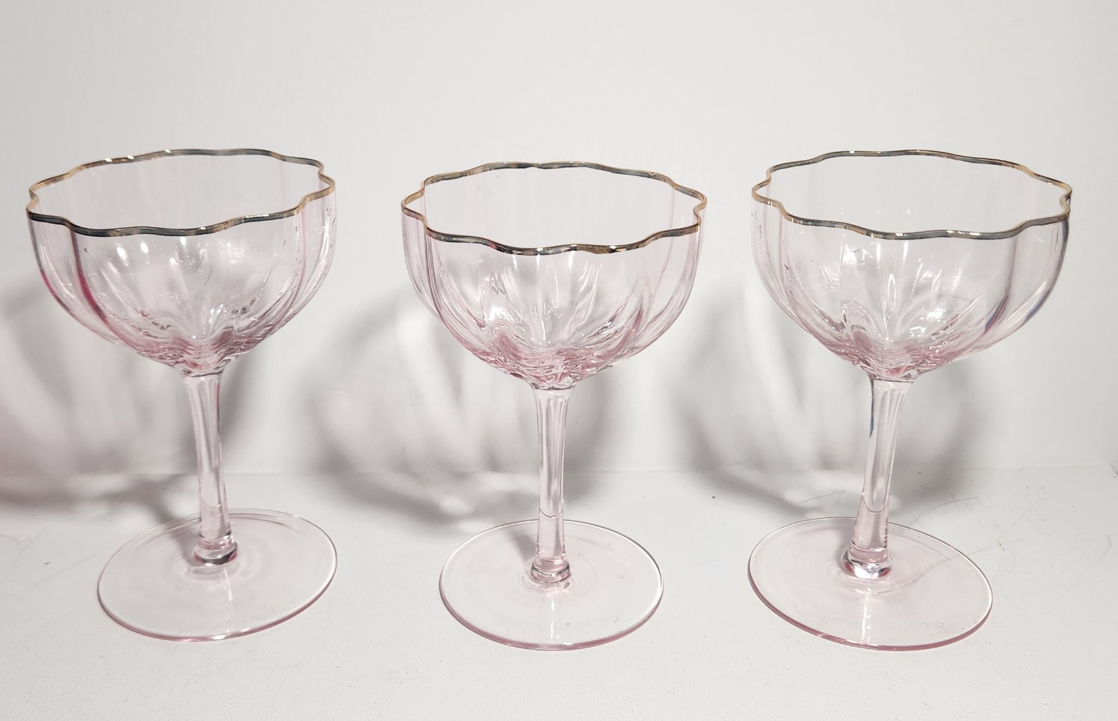 Set of three pink coupe glasses with gold trim and fluted bowls