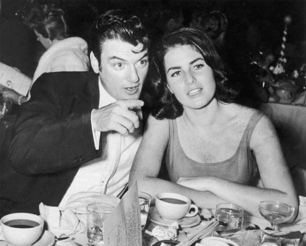 William Campbell sits wife Judith Exner Campbell at a table pointi- Old Photo