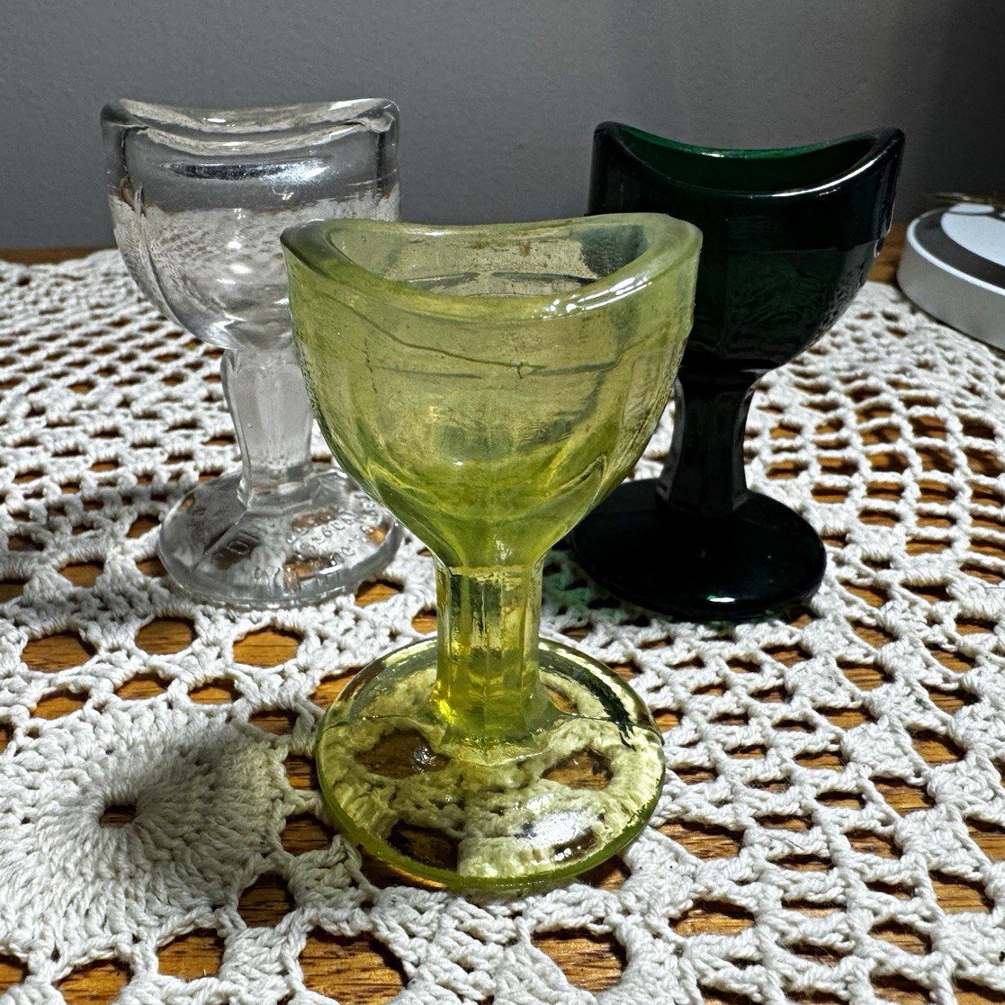 Three vintage eye wash cups. One with very strong UV glow. ￼
