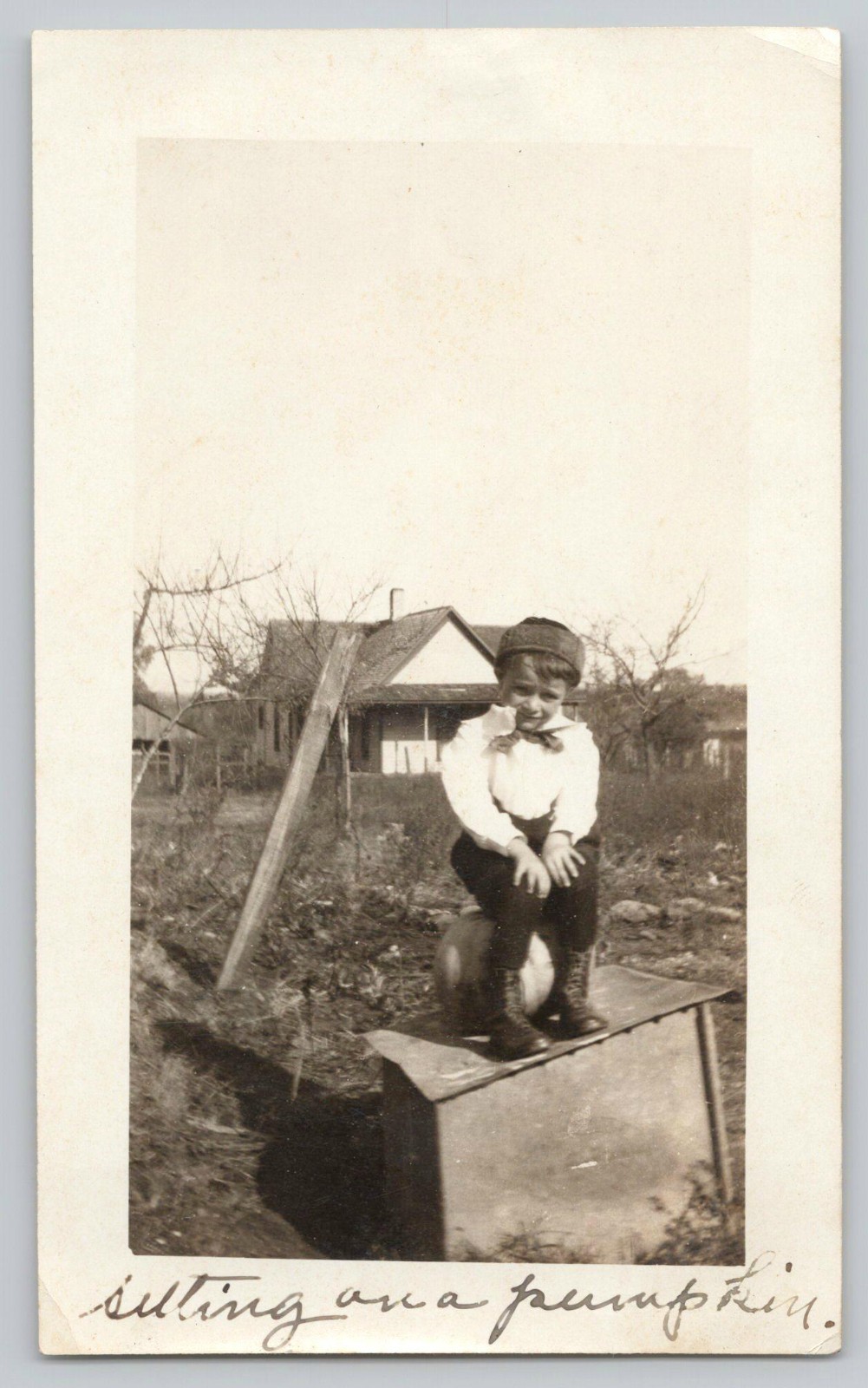 1920s Cute Boy Flat Cap Sitting on Pumpkin near Rural Farmhouse Antique Photo