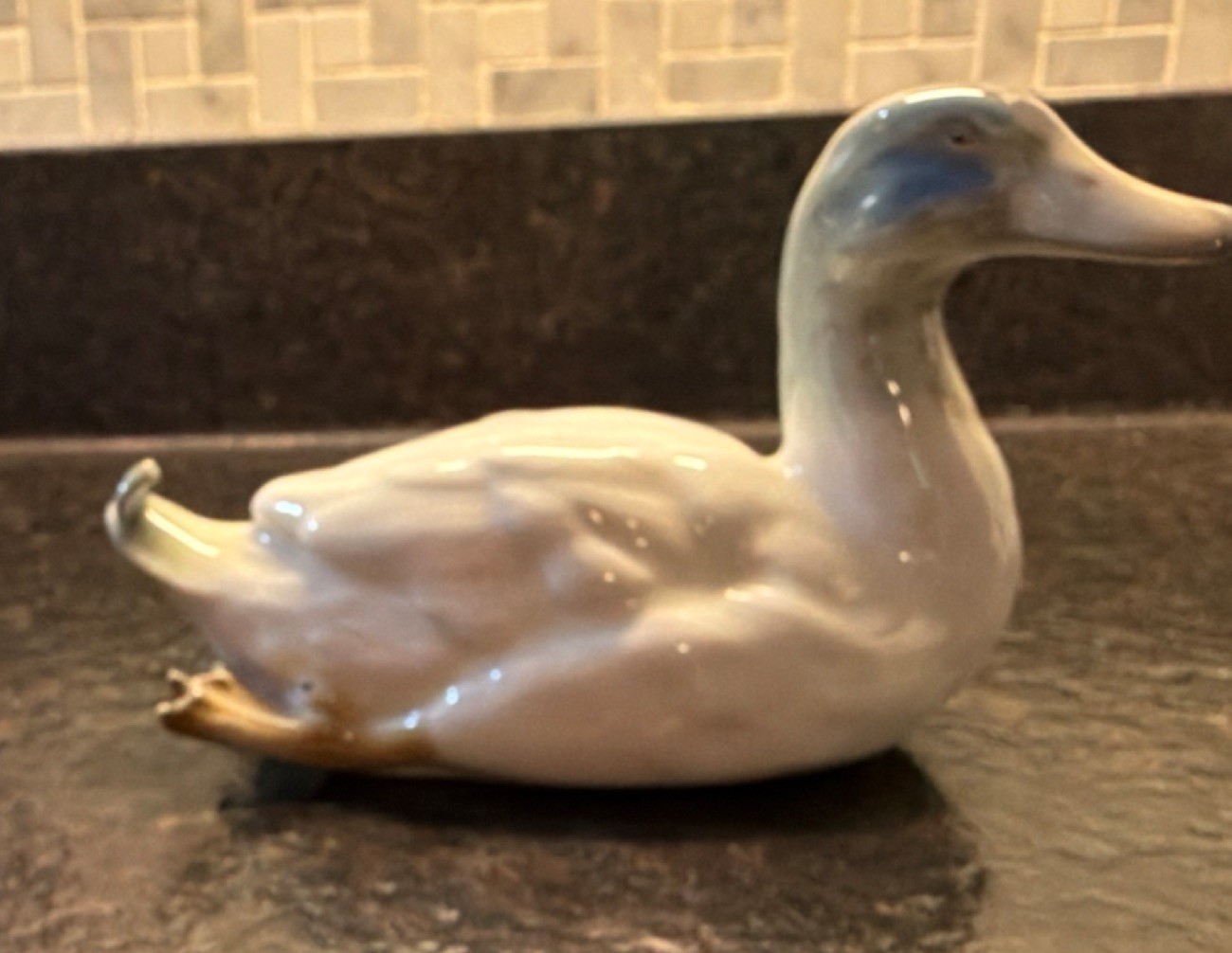 A vintage Gebrüder Heubach porcelain duck figurine with grey and blue accents.