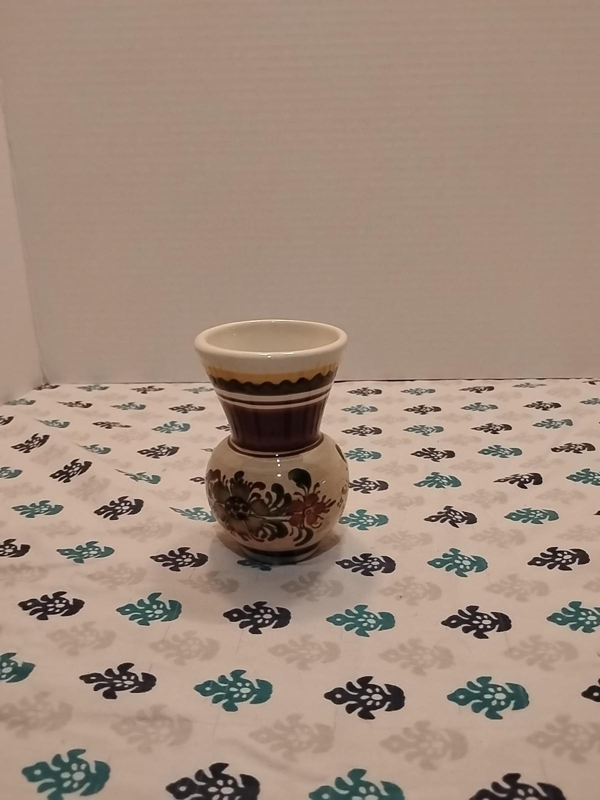 small, hand-painted ceramic vase with a floral design.