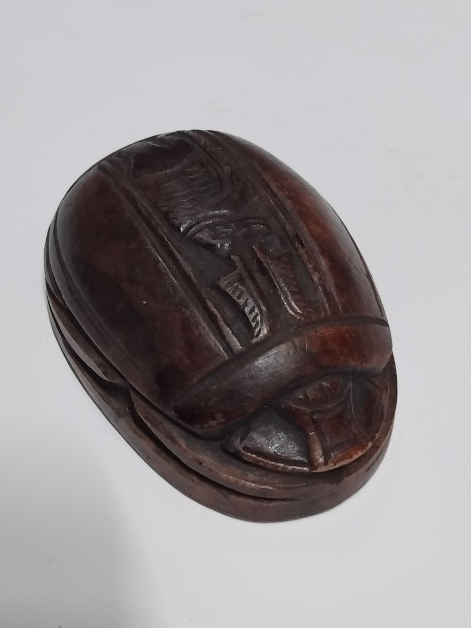 A collectible scarab made of carved dark brown stone featuring an Egyptian style