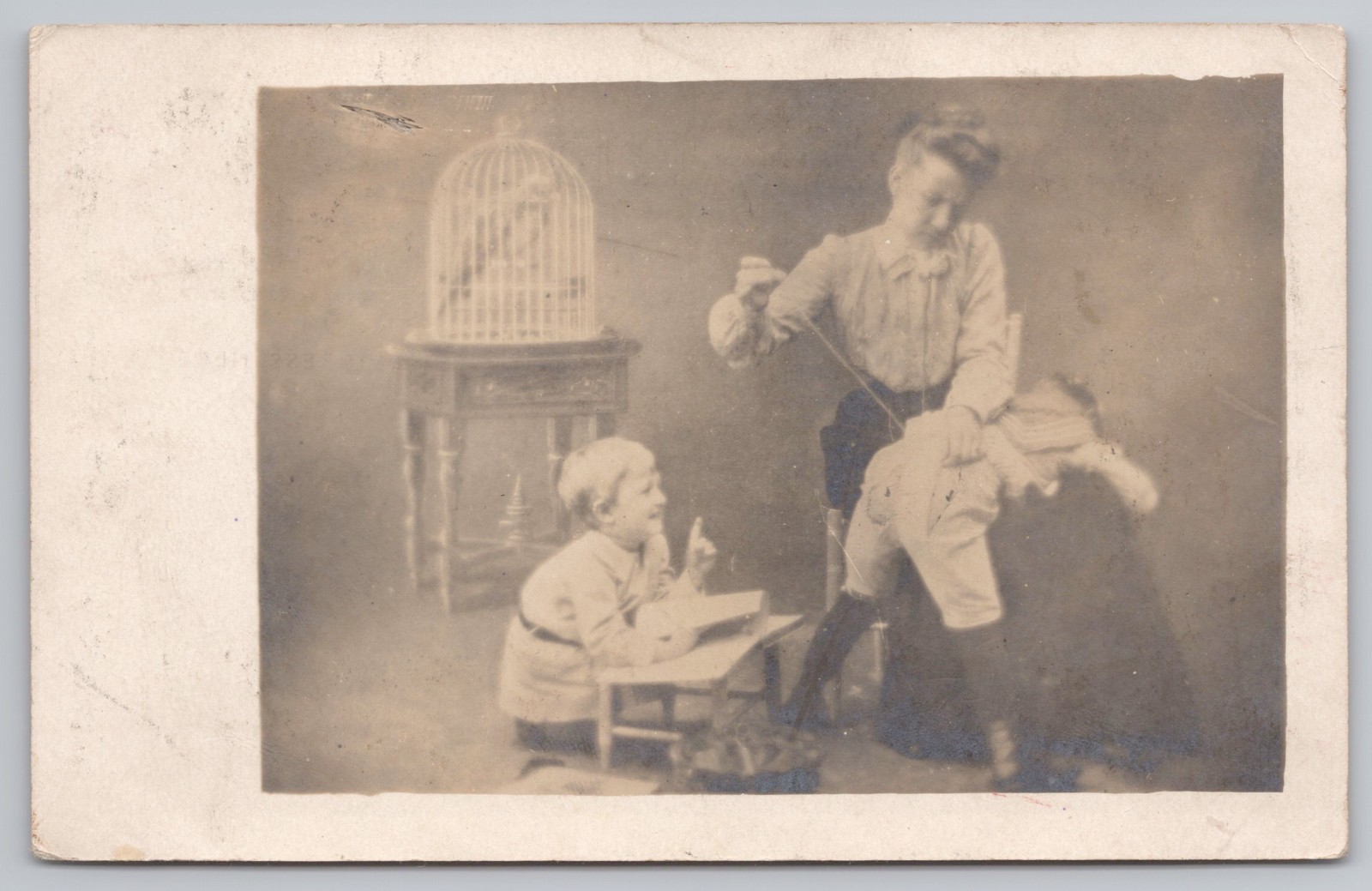 RPPC Posted 1909 Funny Studio Photo Postcard Woman Sewing Child's Pants Birdcage
