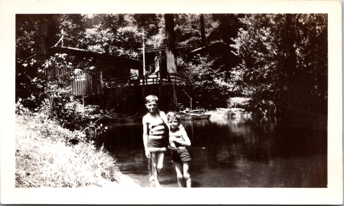 Two Boys Swimming by River Cabin, 1930s B&W Snapshot Photo