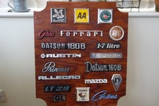 A DISPLAY BOARD COVERED IN VINTAGE CAR BADGES 0VERALL  20 X 17.75 INCHES picture