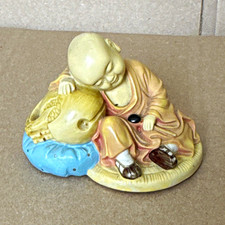 Ceramic Monk Figurine Resting on Blue Cushion Beige Brown Blue Religion Theme picture