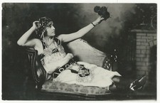 AN ALLURING YOUNG WOMAN BECKONING FROM A LOVESEAT  (RPPC) picture