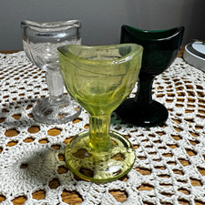 Three vintage eye wash cups. One with very strong UV glow. ￼ picture