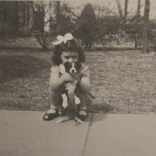 Vintage B&W Photo Snapshot of Young Girl Crouching While Holding up Puppy picture