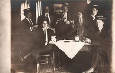 VINTAGE POSTCARD REAL PHOTO CARD GROUP TOASTING WITH BOTTLES TABLES AND SMILES picture