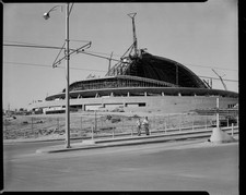 Two men leaning fence front of Civic Arena construction partially - Old Photo picture