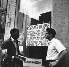 Two men a woman stand front of signs that read Register Vote Basin- Old Photo picture