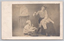 RPPC Posted 1909 Funny Studio Photo Postcard Woman Sewing Child's Pants Birdcage picture